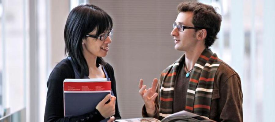 Two students in discussion while holding books