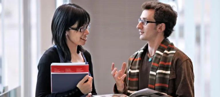 Two students in discussion while holding books